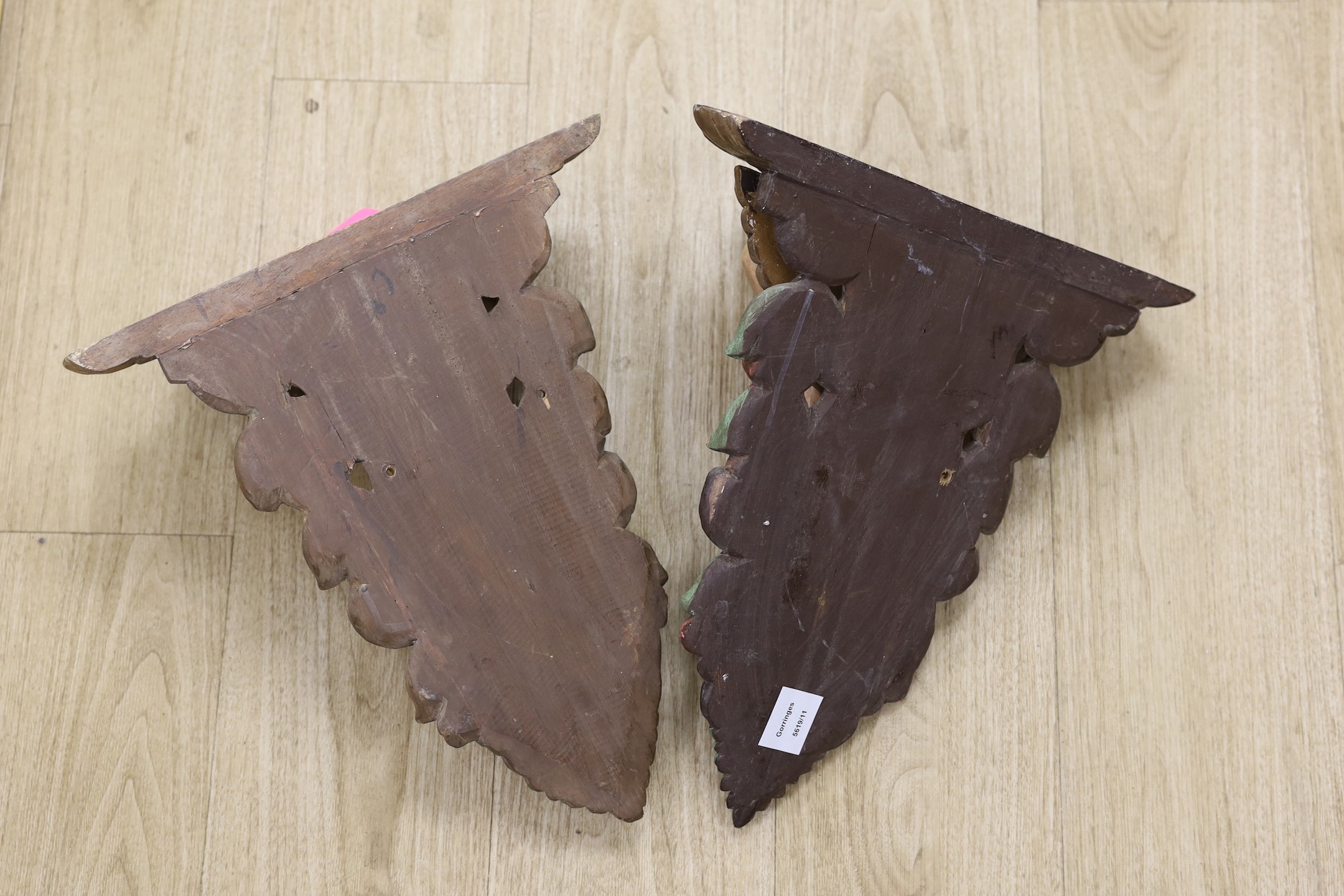 A pair of painted wooden cherubic wall brackets, 42cm tall